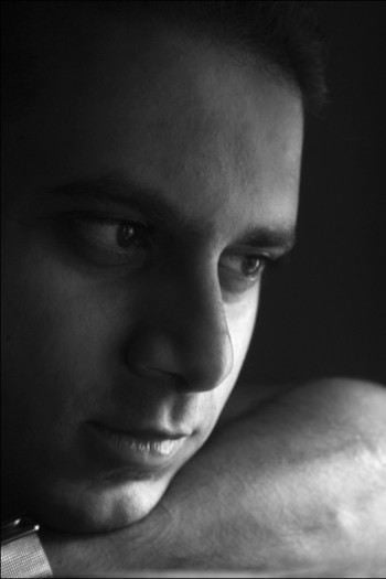 Photograph of a man resting his chin on his arm looking intently