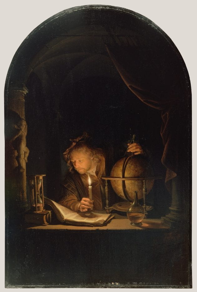 Astronomer with hands on globe reading by candlelight