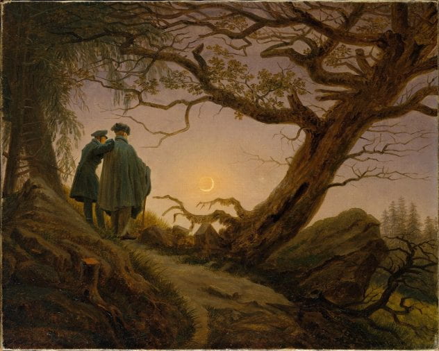 Two men standing under a tree in the wilderness looking up at the moon.